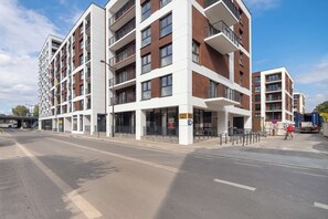 A multi-story residential building with balconies, a pedestrian pathway, and a clear sky. - Modern Apartment in the City Center | Balcony (Łódź)