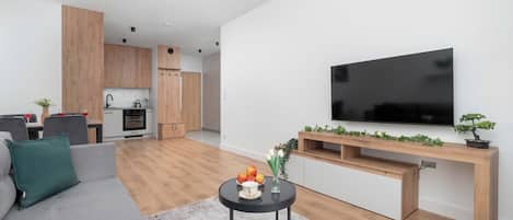 A modern living space with a kitchen, dining area, and a flat-screen TV mounted on the wall.