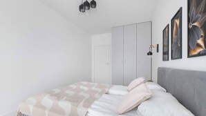 A modern bedroom with a bed, a wardrobe, and wall-mounted artwork. - Modern Apartment in the City Center | Balcony (Łódź)