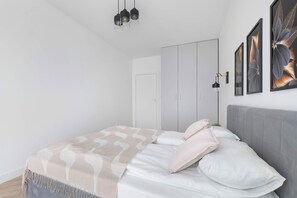 Une chambre moderne avec un lit, une armoire et des œuvres d’art accrochées au mur.