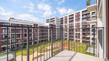 Um complexo de apartamentos moderno com várias varandas, um pátio central e céu limpo.