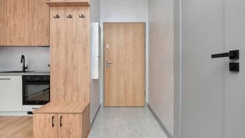 Cozinha moderna com armários de madeira, forno embutido e micro-ondas branco fixado na parede.