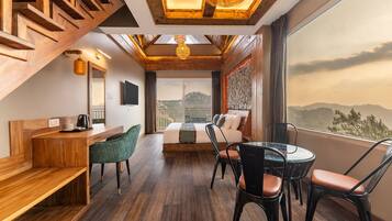 A modern hotel room with a wooden staircase, a bed, a desk, and a dining area.