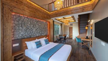 Une chambre spacieuse avec un grand lit, un mur décoratif en pierre, un coin repas et un escalier menant à un niveau supérieur.