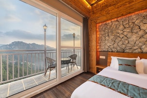 Habitación de hotel con un balcón grande, una cama con colcha y una pared de piedra.