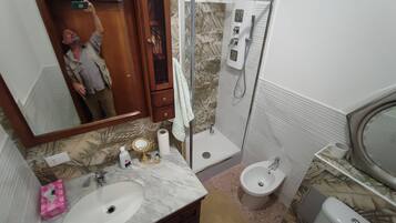 A bathroom with a sink, mirror, vanity, shower, toilet, and a towel rack.