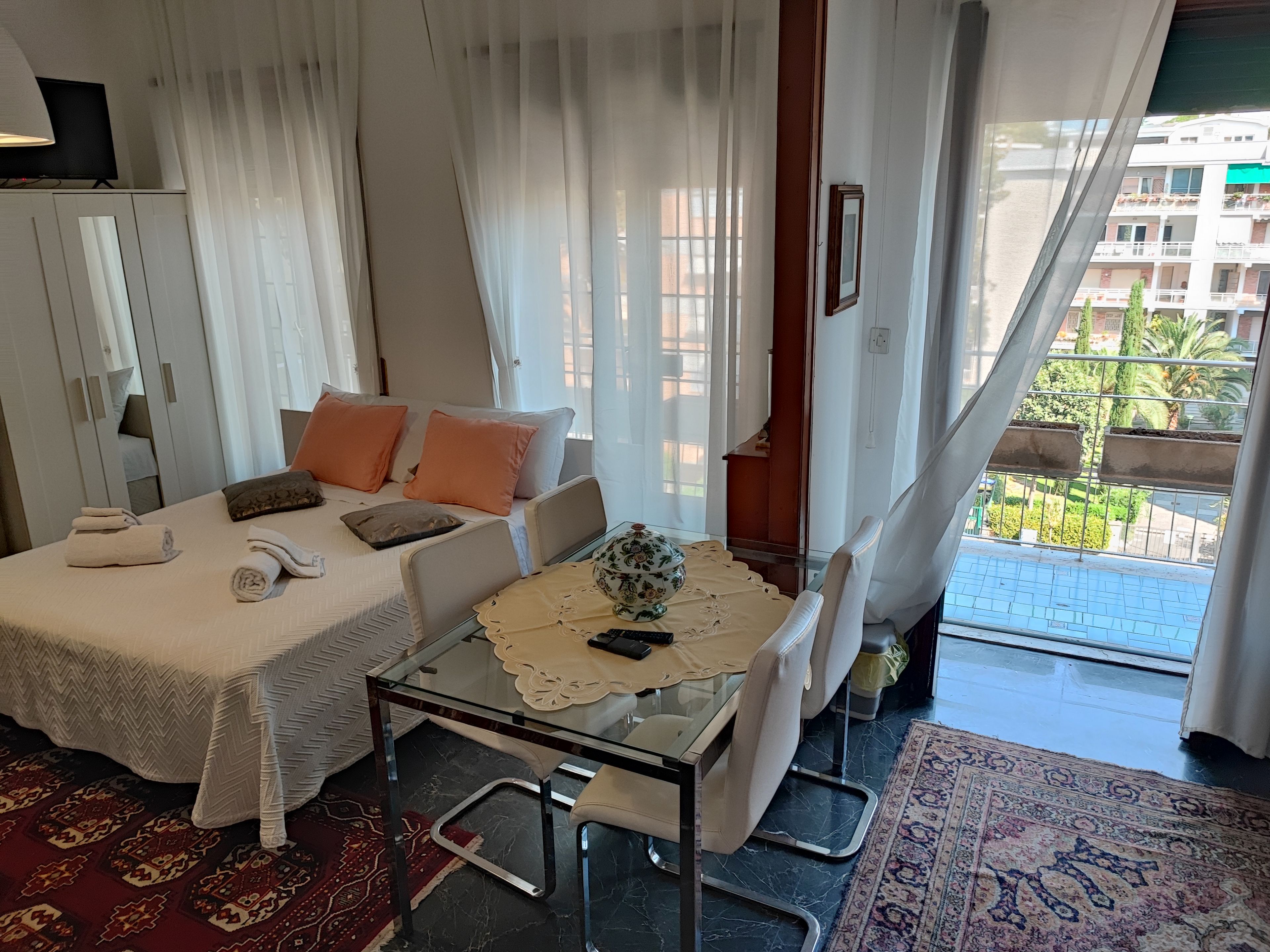Hotelkamer met een bed, een glazen tafel, een stoel, een klein tafeltje met decoratie en uitzicht op het exterieur.