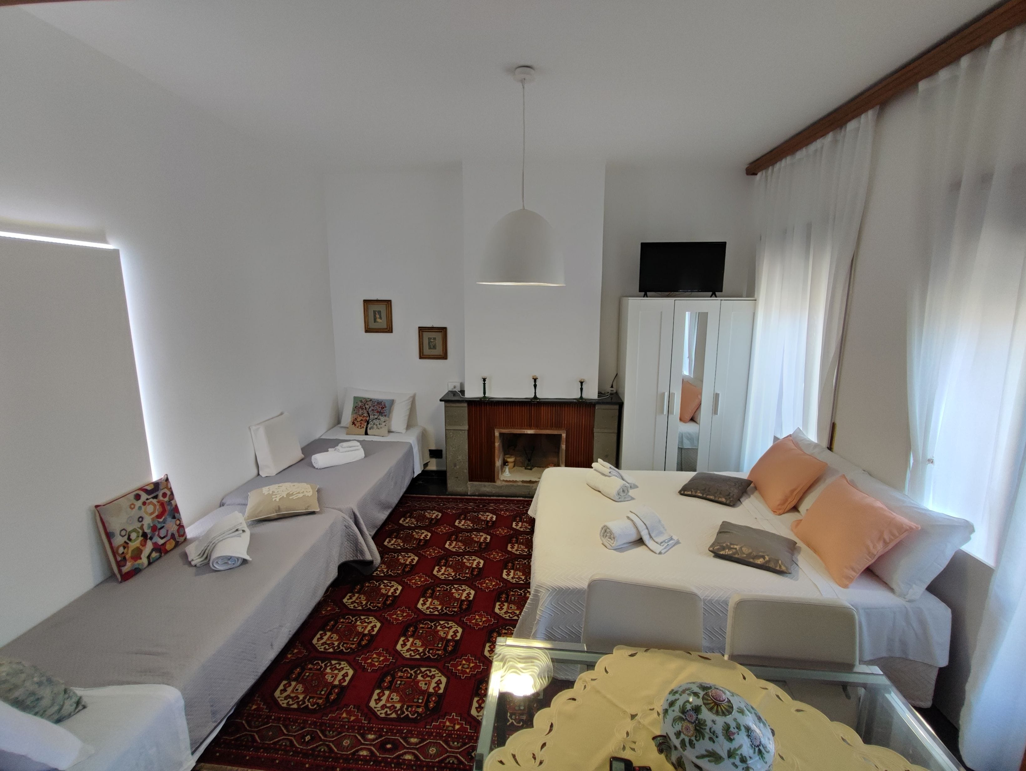Een hotelkamer met twee bedden, een open haard, een televisie en een kledingkast.