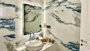 A bathroom with a marble sink, a mirror, and a door. - White & black Suites – Suite Five (Σίφνος)