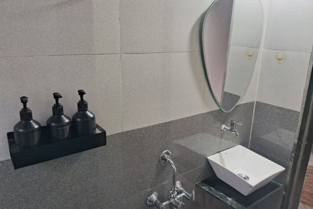 A bathroom with a white sink, a glass shower enclosure, and a black soap dispenser holder.
