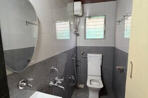 A bathroom with a toilet, a shower, and a sink.