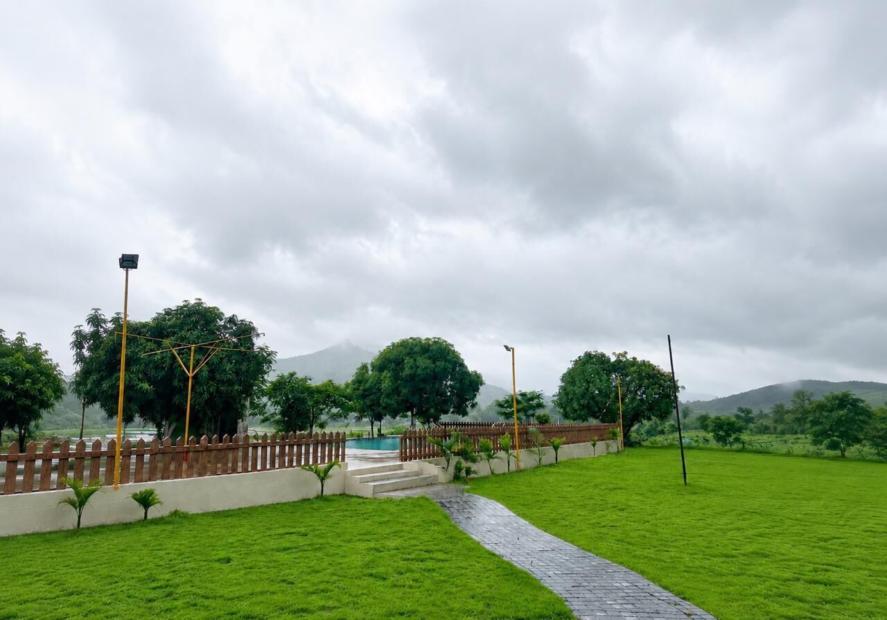 A paved pathway leading to a wooden fence and a pool area with a mountain backdrop.