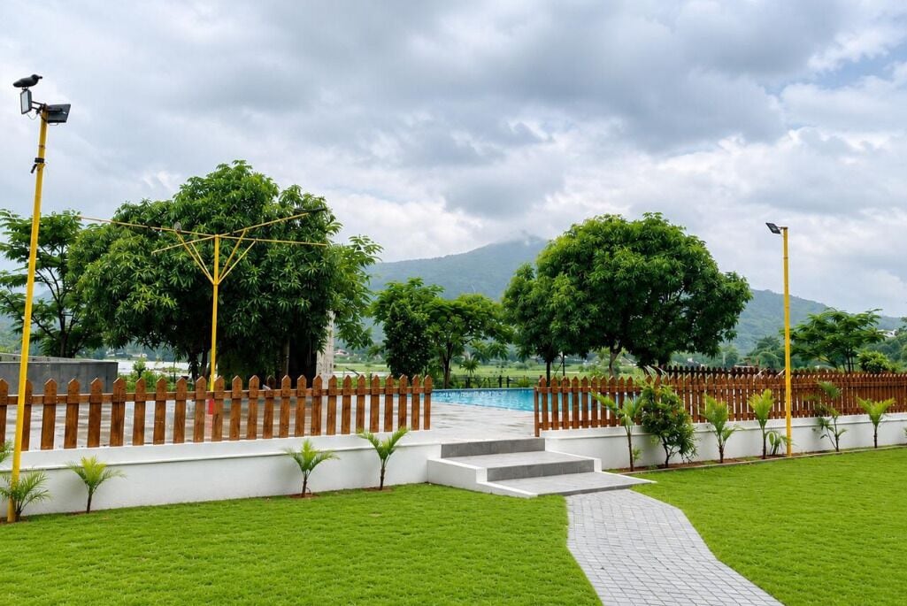 A landscaped area with a pool, wooden fence, and steps leading to a building.