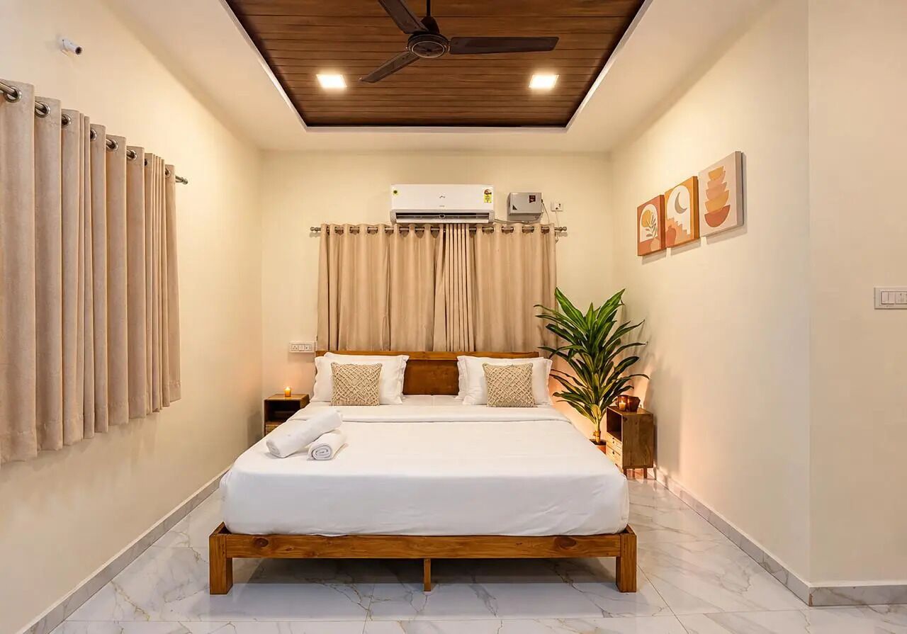 A bedroom with a wooden bed, beige curtains, an air conditioning unit, and a ceiling fan.