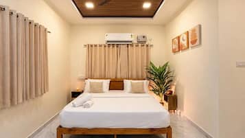 A bedroom with a wooden bed, beige curtains, an air conditioning unit, and a ceiling fan.