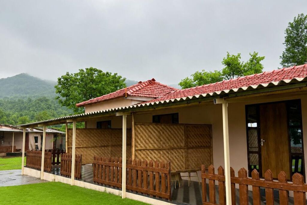 A row of cabins with red-tiled roofs, wooden fences, and a view of green hills.