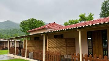 A row of cabins with red-tiled roofs, wooden fences, and a view of green hills.
