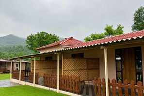 A row of cabins with red-tiled roofs, wooden fences, and a view of green hills.