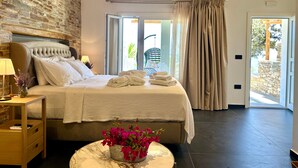 A bedroom with a bed, bedside table, lamp, and a potted plant. - White & black Suites – Suite Five (Platis Yialos Sifnos)