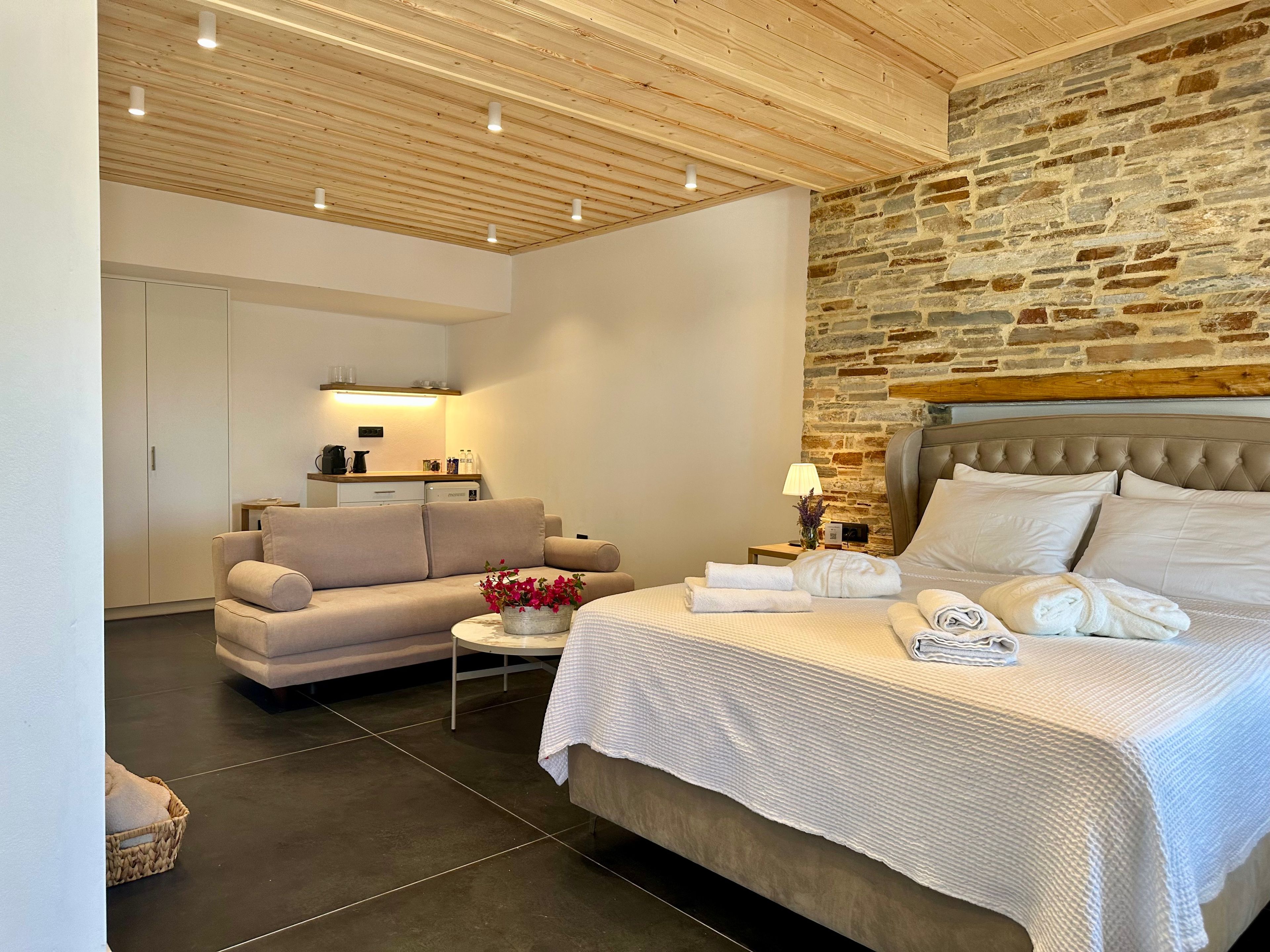 Une chambre à coucher moderne avec un lit, un canapé, une petite table et une armoire.