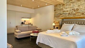 A modern bedroom with a bed, a sofa, a small table, and a wardrobe.