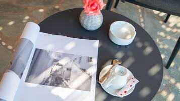 Une table ronde avec un magazine, un vase contenant une fleur, une tasse et une soucoupe.