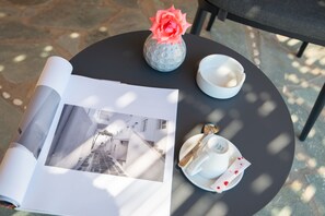 A round table with a magazine, a vase with a flower, a cup, and a saucer.