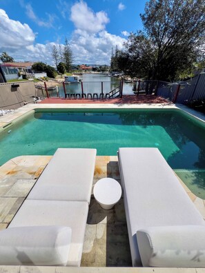 A rectangular swimming pool with two lounge chairs and a small round table. - Waterfront Retreat with Pool & Pontoon, Broadbeach (Broadbeach Waters)