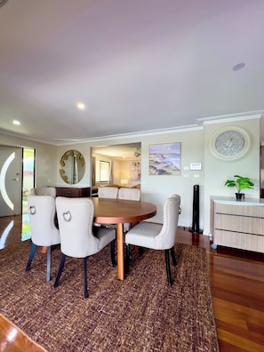 A dining area with a round table and four chairs, a large mirror, and a clock on the wall. - Waterfront Retreat with Pool & Pontoon, Broadbeach (Broadbeach Waters)