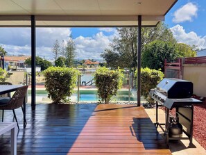 A covered outdoor area with a pool, a barbecue grill, and a table with chairs. - Waterfront Retreat with Pool & Pontoon, Broadbeach (Broadbeach Waters)