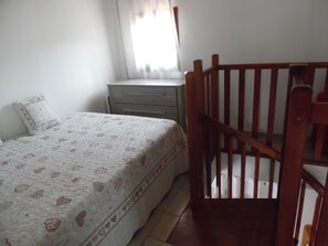 A bedroom with a bed, a wooden crib, a nightstand, and a window with curtains. - Small house 2 km from the sea (villeneuve-Loubet)