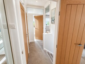 A hallway with wooden doors, a white wall, and a carpeted floor. - House Sleeps 4 With Parking (Sutton Coldfield)