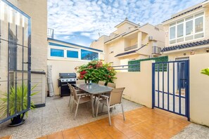 A patio with a table and chairs, a grill, and a gate. - Bungalow ', La Veleta' with Mountain View, Shared Pool and Wi-Fi (Torrevieja)