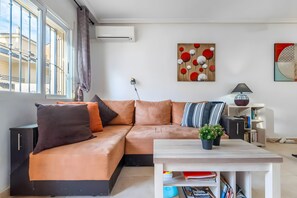 Ein modernes Wohnzimmer mit einem Ecksofa, einem Couchtisch, einem Bücherregal und einem Gemälde an der Wand.