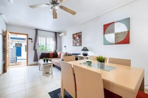Ein modernes Wohnzimmer mit einer Couch, einem Esstisch und einem Deckenventilator.