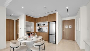 Cozinha moderna com ilha central, eletrodomésticos embutidos e área de refeições com quatro cadeiras.