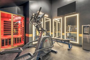 Ein Fitnessstudio mit Trainingsgeräten, Spiegeln und einem Wasserspender.