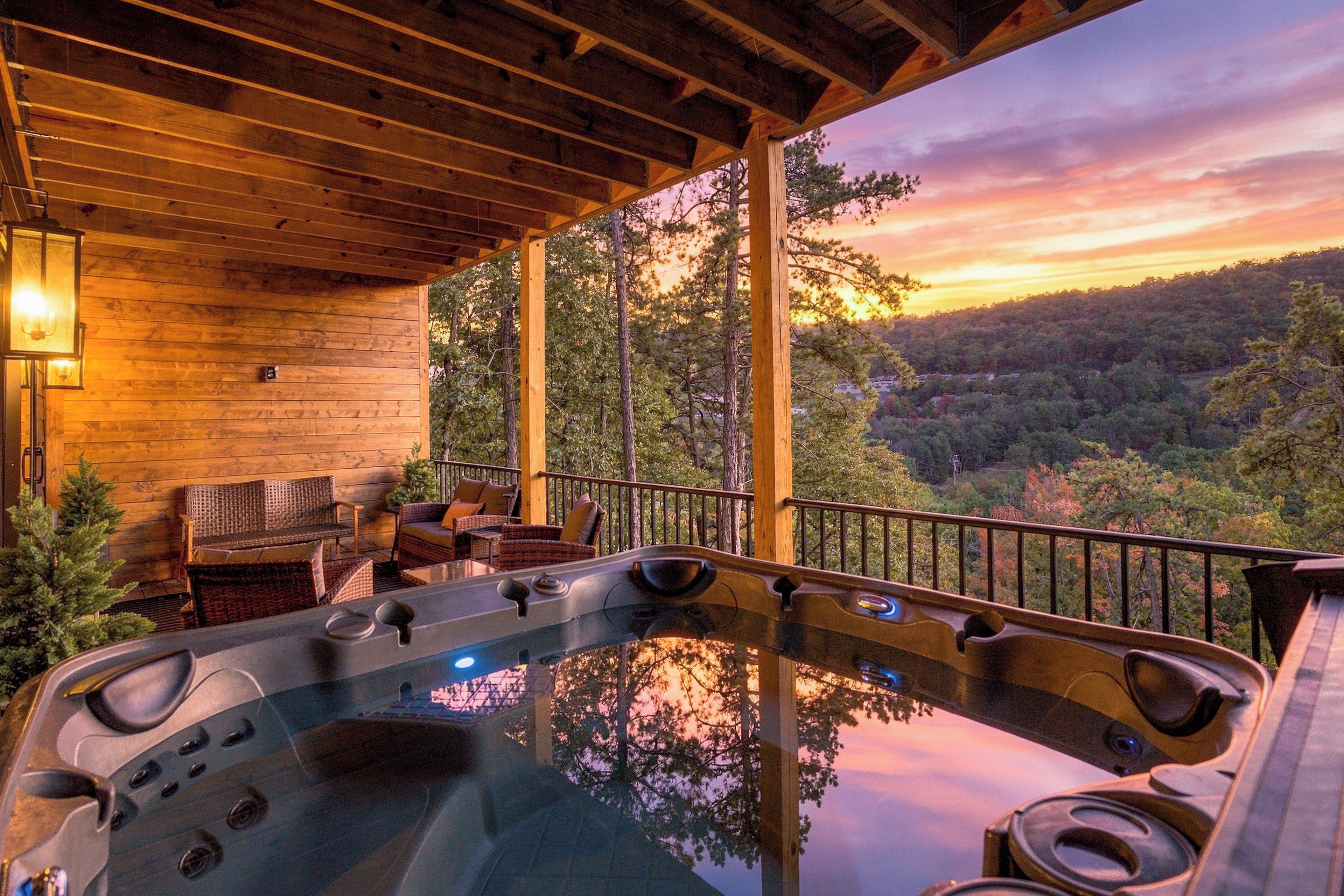 A hot tub on a wooden deck with a view of a forested landscape.