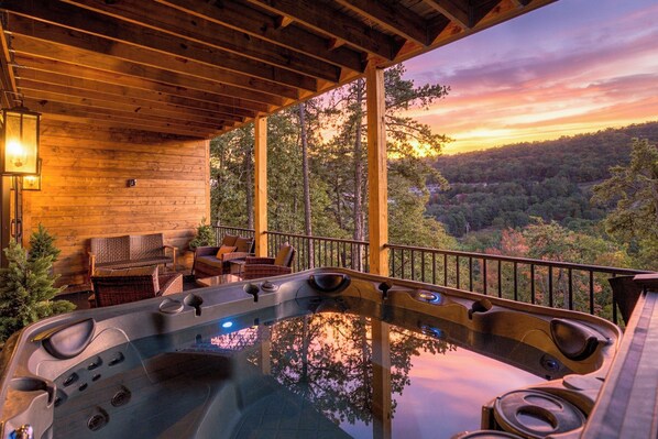 A hot tub on a wooden deck with a view of a forested landscape.