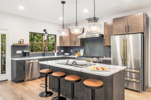 A modern kitchen with a central island, stainless steel appliances, and a herringbone backsplash.