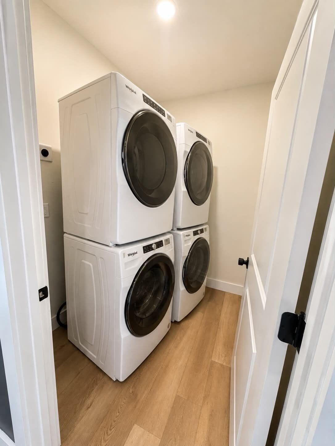 A laundry room with two stacked front-loading washers and dryers.