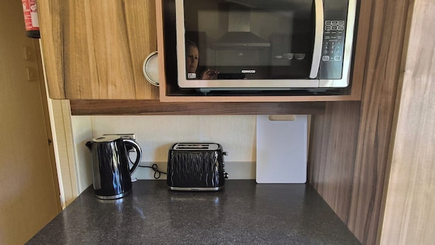 A kitchen with a microwave, toaster, and kettle on a countertop.