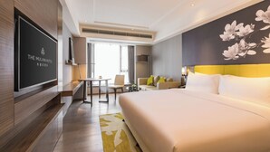 A hotel room with a large bed, a flat-screen TV, a dining table, and a sofa. - The Mulian Hotel (Chengdu)