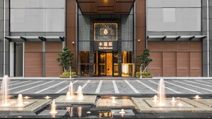 A hotel entrance with a modern facade, a sign reading 'The Mulian,' and a water feature in front. - The Mulian Hotel (Chengdu)