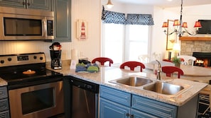 A kitchen with stainless steel appliances, a granite countertop, and a dining area with red chairs.