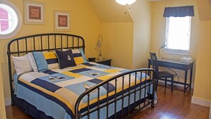 A bedroom with a bed, a desk, and a chair.