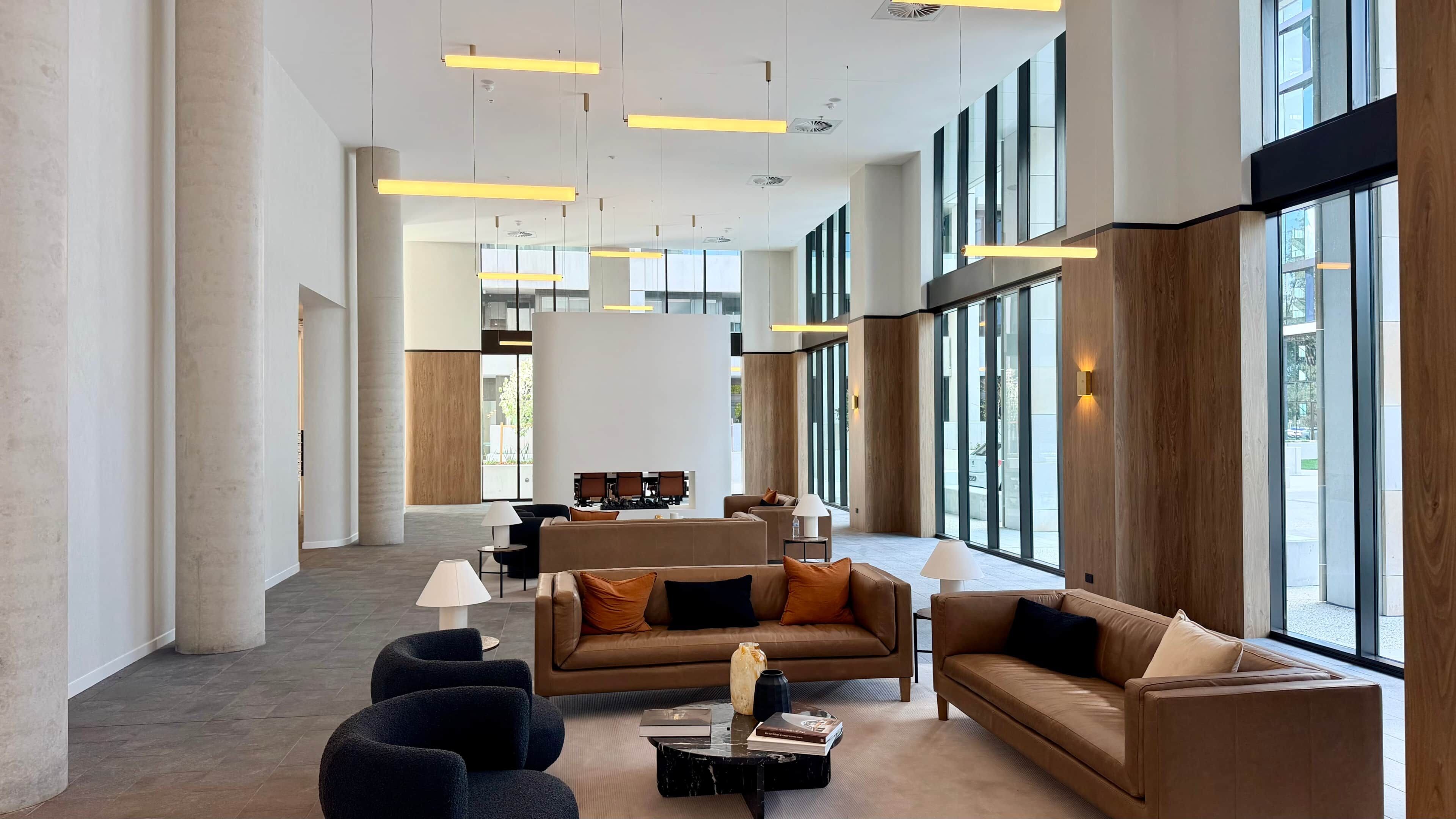 A spacious lobby with high ceilings, modern furniture, and large windows allowing natural light.