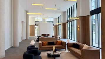 A spacious lobby with high ceilings, modern furniture, and large windows allowing natural light.