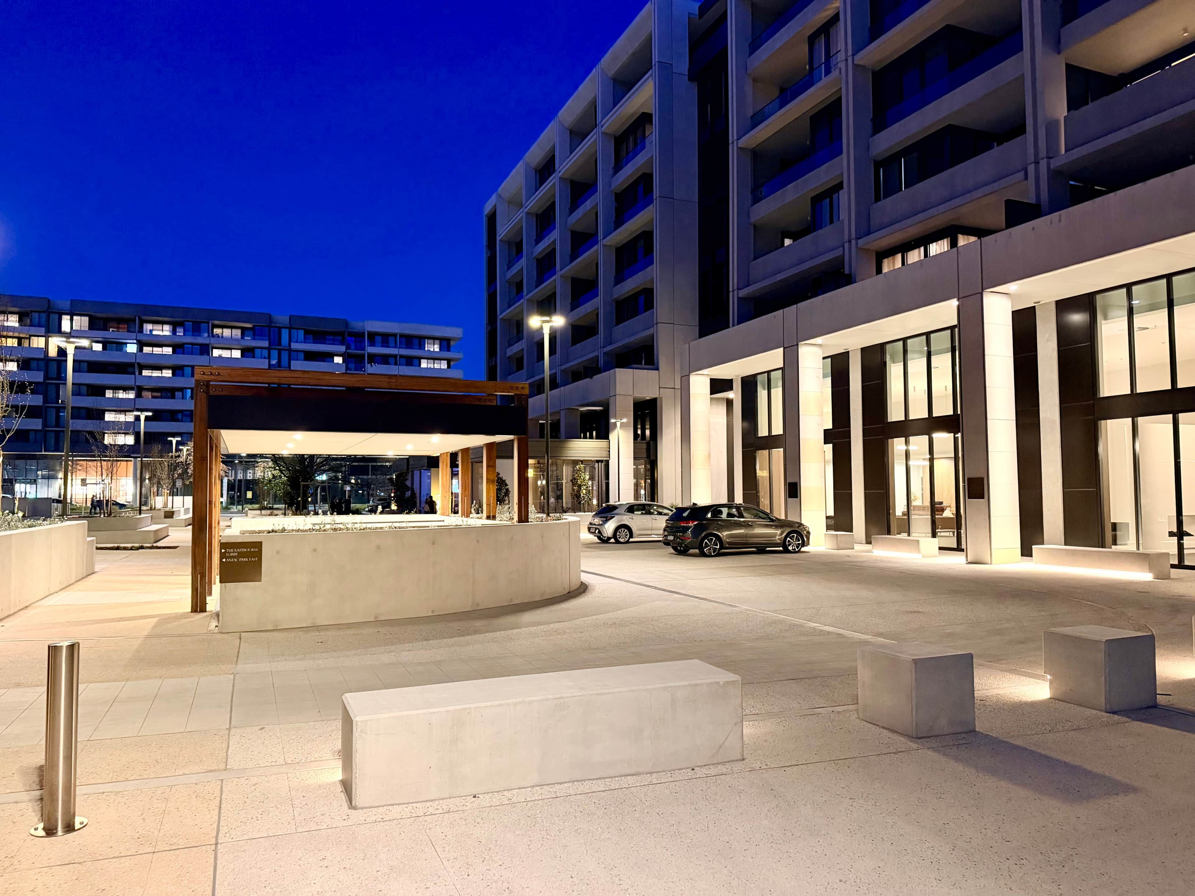 A modern building with a covered outdoor seating area and a parking lot.