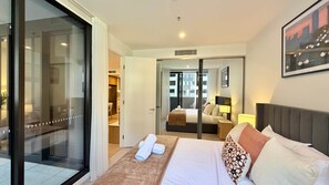 Ein Hotelzimmer mit Bett, Bad und einer Glastür, die auf einen Balkon führt.